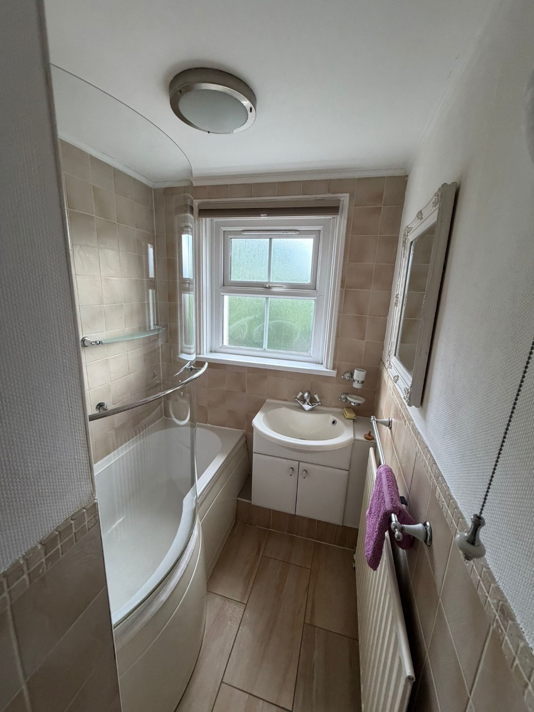 Finished bathroom with shower bath, vanity basin, radiator and tiled floor