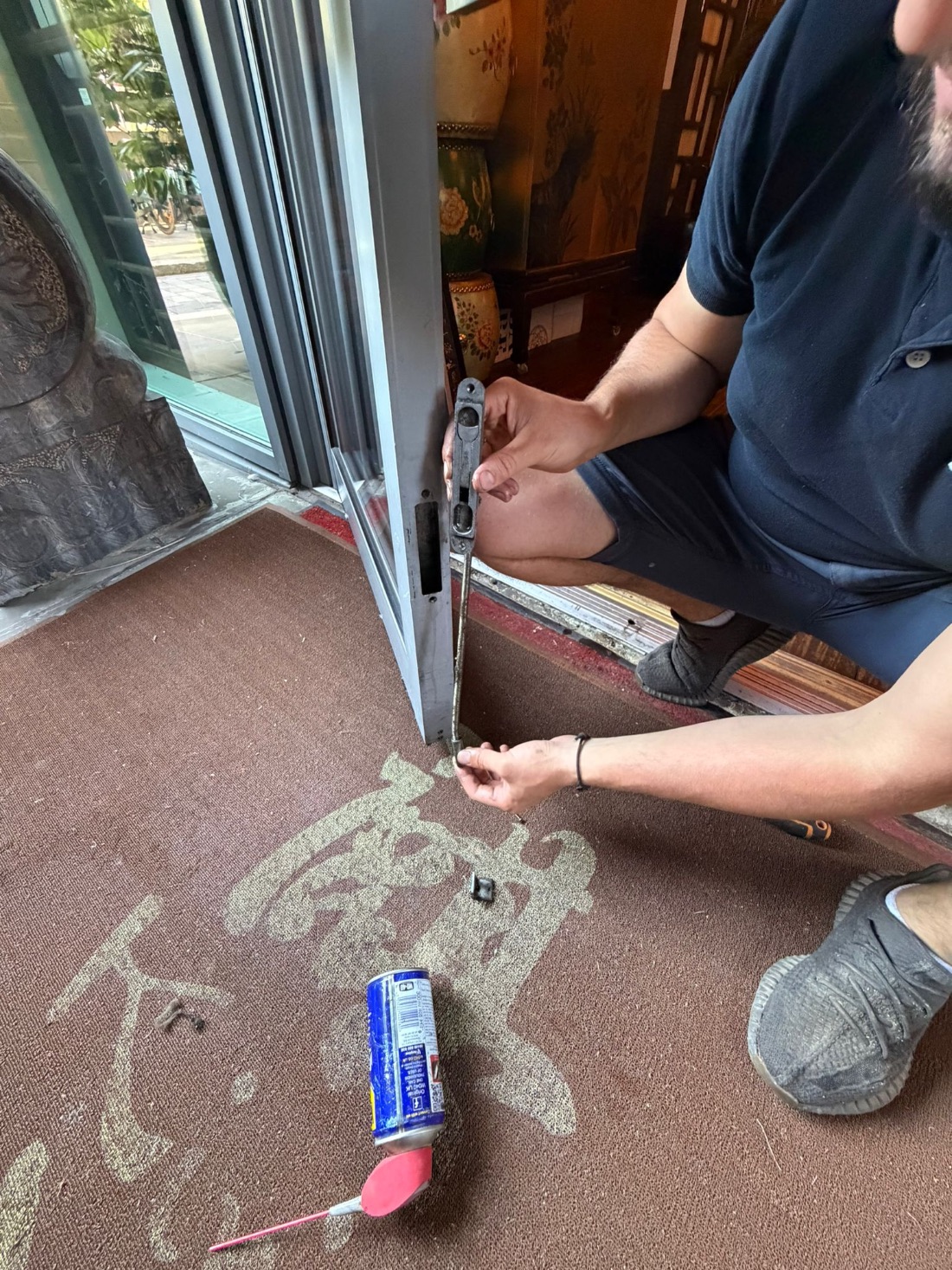 BW operative removing a worn floor spring and flush bolt from a commercial glazed shopfront door